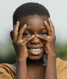 portrait-smiley-african-child-holding-hands-face